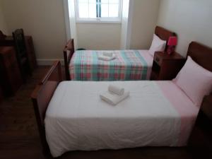 1 dormitorio con 2 camas y toallas blancas. en A Casa da Matriz, en Madalena