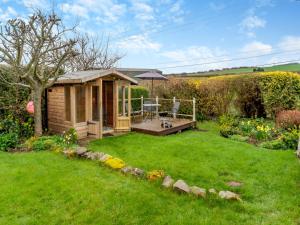 Cabaña de madera en un patio con césped verde en Dotty Cottage en Ellingham