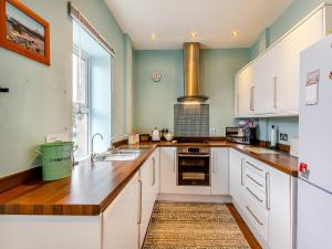 cocina grande con armarios blancos y fregadero en Dotty Cottage en Ellingham