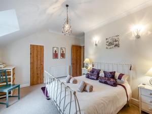een slaapkamer met een groot bed en een kroonluchter bij Dotty Cottage in Ellingham