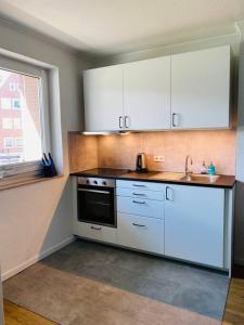 a kitchen with white cabinets and a sink and a window at Zentrale Studio Wohnung in Emden in Emden