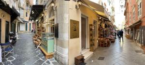 a narrow street with shops on both sides of a building at Biscoutsis old town studio in Corfu