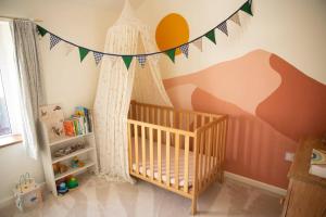 - une chambre bébé avec un lit bébé et un mur de montagne dans l'établissement Family-friendly Cottage in the heart of St Columb, à Saint Columb Major