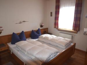 łóżko z białą pościelą i niebieskimi poduszkami w obiekcie Weissensee holiday home w Füssen