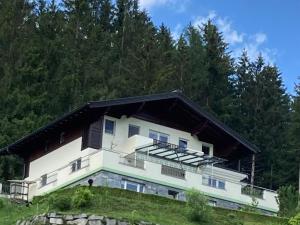 uma grande casa branca numa colina com árvores em Holiday apartment in Pinzgau with a large terrace em Mittersill