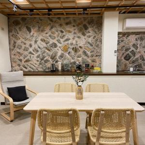 una mesa y sillas en una habitación con una pared de piedra en 小島上二館, en Chung-liu-ts'un