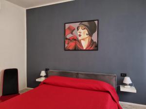 una camera con letto rosso e dipinto di una donna di Solino House a Capoliveri
