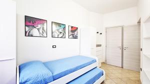 a white bedroom with a blue bed and pictures on the wall at Casa Iris in Capoliveri