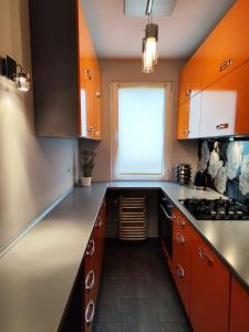 La cuisine est équipée d'armoires orange et d'un four avec plaques de cuisson. dans l'établissement Apartament Arena, à Zgorzelec