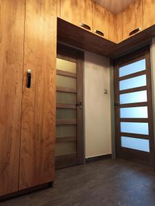a walk in closet with wooden cabinets and a door at Apartament Arena in Zgorzelec