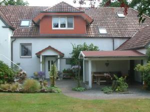 a white house with a red roof and a patio at Ferienwohnung am Reiherbach in Bielefeld