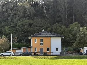 een geel en wit huis met auto's geparkeerd in een veld bij Ferienhaus mit 4 Zimmer am Lech in Reutte