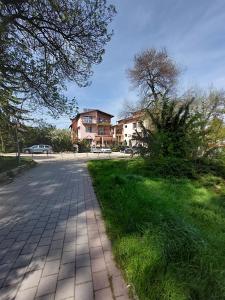 a brick road with houses in the background with grass and trees at Къща за гости Хриси in Velingrad