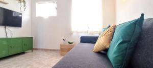 uma sala de estar com um sofá com almofadas e uma televisão em Casa do Sol em Albufeira