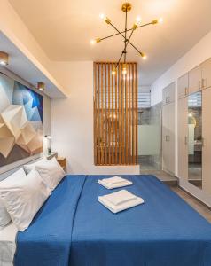 a bedroom with a blue bed and a chandelier at Theo's Cozy Apartment near Athens airport in Spata