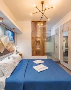 a bedroom with a blue bed and a chandelier at Theo's Cozy Apartment's near Athens airport in Spáta