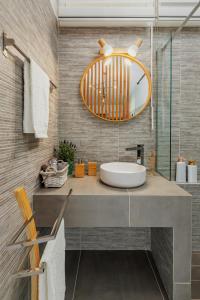 uma casa de banho com um lavatório e um espelho grande em Theo's Cozy Apartment near Athens airport em Spata