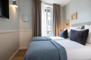 a hotel room with two beds and a window at Le Petit Oberkampf Hotel & Spa in Paris