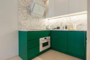 a kitchen with green cabinets and a white oven at VacationClub - Let’s Sea Baltic Park B42 in Gąski
