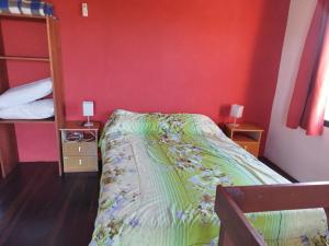 1 dormitorio con cama y pared roja en Alas del Mar, en Punta del Diablo