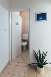 La salle de bains est pourvue de toilettes et d'une plante. dans l'établissement Villa Porta, à Biograd na Moru
