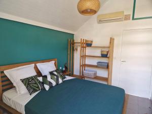 Schlafzimmer mit einem Bett mit blauer Wand in der Unterkunft Joli Duplex 6 pers. avec piscine in Le Diamant