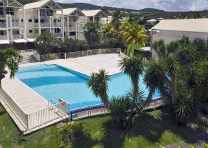 an overhead view of a large swimming pool with palm trees at Joli Duplex 6 pers. avec piscine in Le Diamant