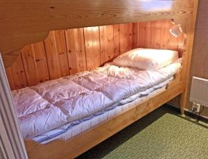 a bed in a wooden room with a wooden wall at Tänndalens Stugby in Tänndalen