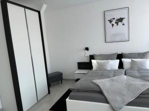 a white bedroom with a bed and a mirror at Zollernalbdomizil FeWo1 in Balingen