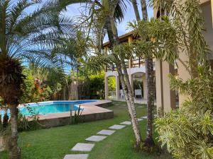 a house with a swimming pool and palm trees at Praia de Taperapuan 7 quartos in Porto Seguro