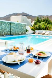 a table with plates of food next to a swimming pool at Mouras Resort in Livadi Astypalaias