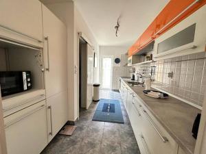 - une cuisine avec des placards blancs et un tapis bleu au sol dans l'établissement Monteview Duplex, à Herceg-Novi