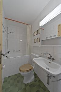 La salle de bains blanche est pourvue de toilettes et d'un lavabo. dans l'établissement Apartment in the heart of Celerina with garden, à Celerina