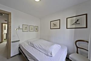 une chambre blanche avec un lit et des photos sur le mur dans l'établissement Apartment in the heart of Celerina with garden, à Celerina