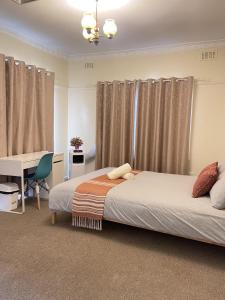a bedroom with two beds and a desk and curtains at Werribee DGH Accommodation in Werribee