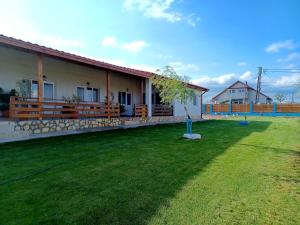 a house with a green lawn in front of it at Pensiunea La Codru in Jurilovca