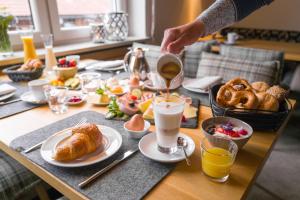 a table with breakfast foods and a person pouring coffee at Natur- & Genießerhotel Der Birkenhof in Oberstaufen
