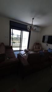 a living room with a couch and a large window at Masion Lovely Home in Ramallah