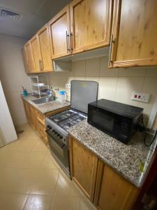 a kitchen with wooden cabinets and a stove top oven at MBZ - Comfortable Room in Unique Flat in Abu Dhabi