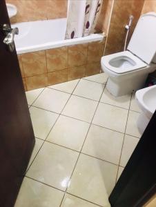 a bathroom with a toilet and a tub and a sink at MBZ - Comfortable Room in Unique Flat in Abu Dhabi