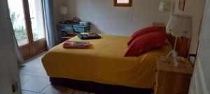 a bedroom with a large bed with a yellow blanket at Gîtes le clos du verger avec piscine chauffée commune in Maurens