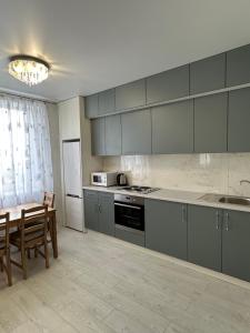 Sky apartments Budova في أوديسا: مطبخ بدولاب رمادية وطاولة وكراسي