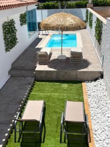 an image of a swimming pool with chairs and an umbrella at The Yumbo Pearl in Playa del Ingles