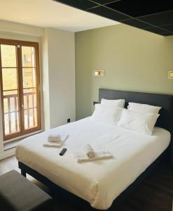 una camera da letto con un grande letto bianco con asciugamani di Hôtel du Château - Beynac et Cazenac a Beynac-et-Cazenac