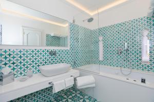 a bathroom with blue and white tiled walls and a sink at Hotel Conca d'Oro in Positano