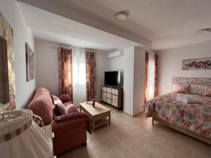 a bedroom with a bed and a couch and a tv at Estudios Costavigía Mazagón by Ramona in Mazagón