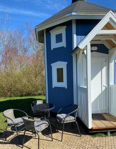 une cabane bleue avec des chaises et une table devant elle dans l'établissement Kroghs Tiny Houses - Hyttebyen, à Grindsted