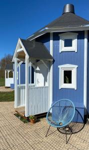 una capanna blu con una sedia blu e una panchina di Kroghs Tiny Houses - Hyttebyen a Grindsted