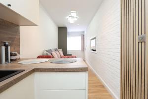 a kitchen with white cabinets and a couch in the background at Peaceful and Novel Place to Stay in Abbey Wood