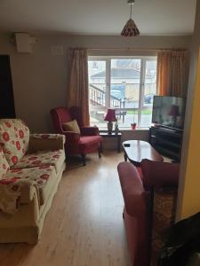 een woonkamer met een bank en stoelen en een televisie bij Kilkenny City Apartment in Kilkenny